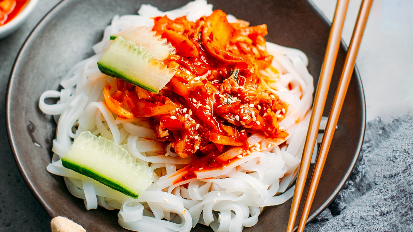 Kimchi topping on noodles in a bowl with chopsticks.