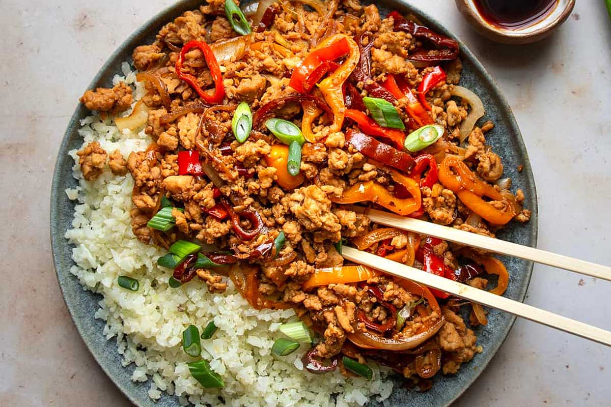 Kung Pao Chicken in a bowl with chopsticks.