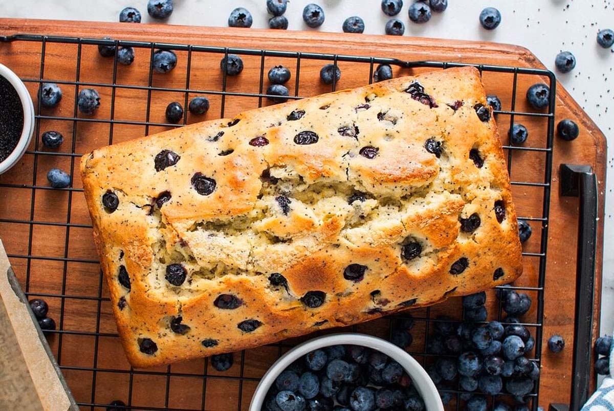A loaf of blueberry bread on a cooling rack.