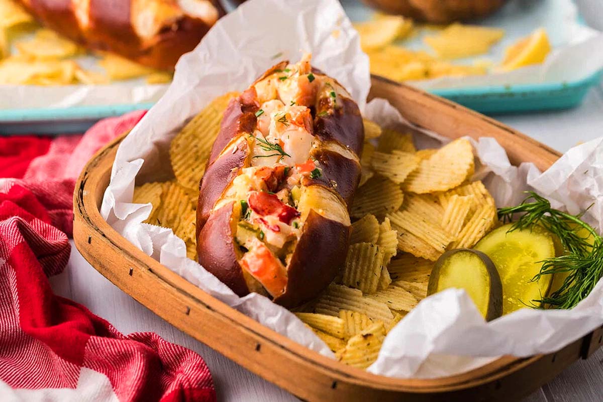 A lobster roll in a basket with potato chops.