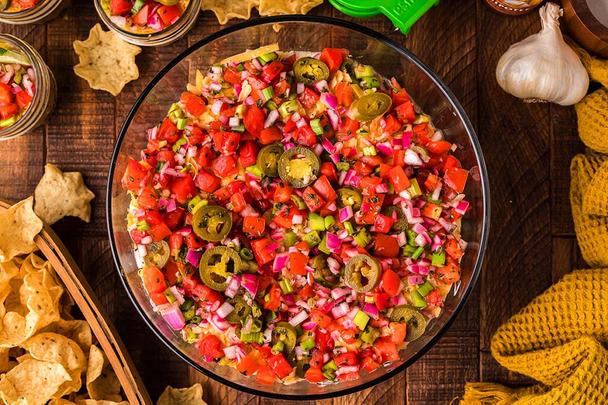 A layered bean dip recipes served with chip scoops.