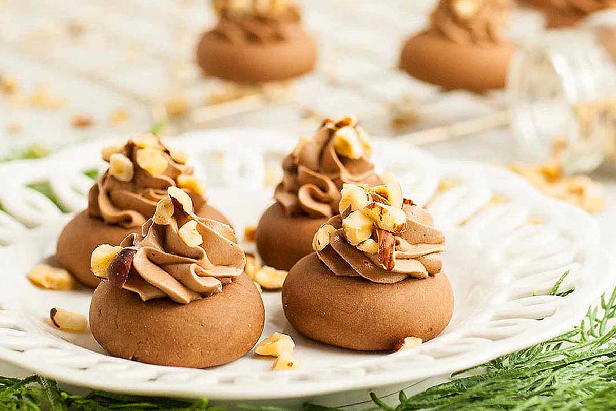Frosted chocolate cookies with chopped hazelnuts on top.