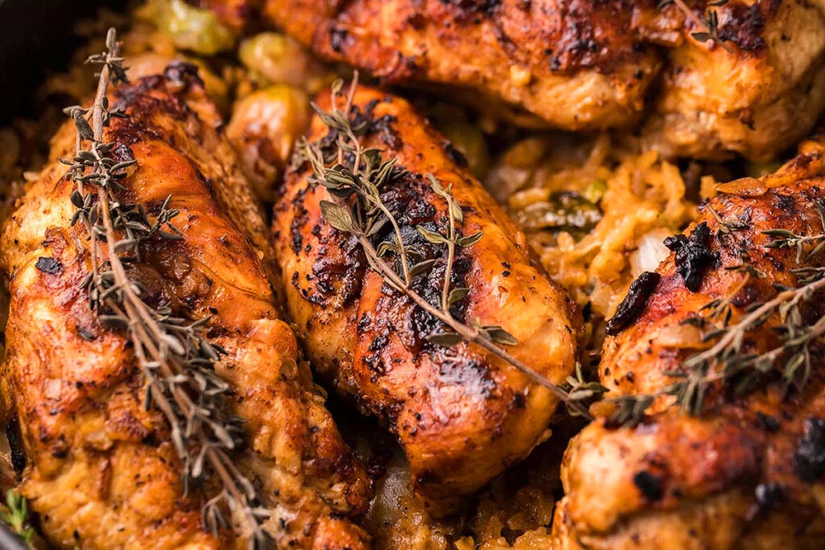 Chicken cooked with rice and fresh herbs in a skillet.
