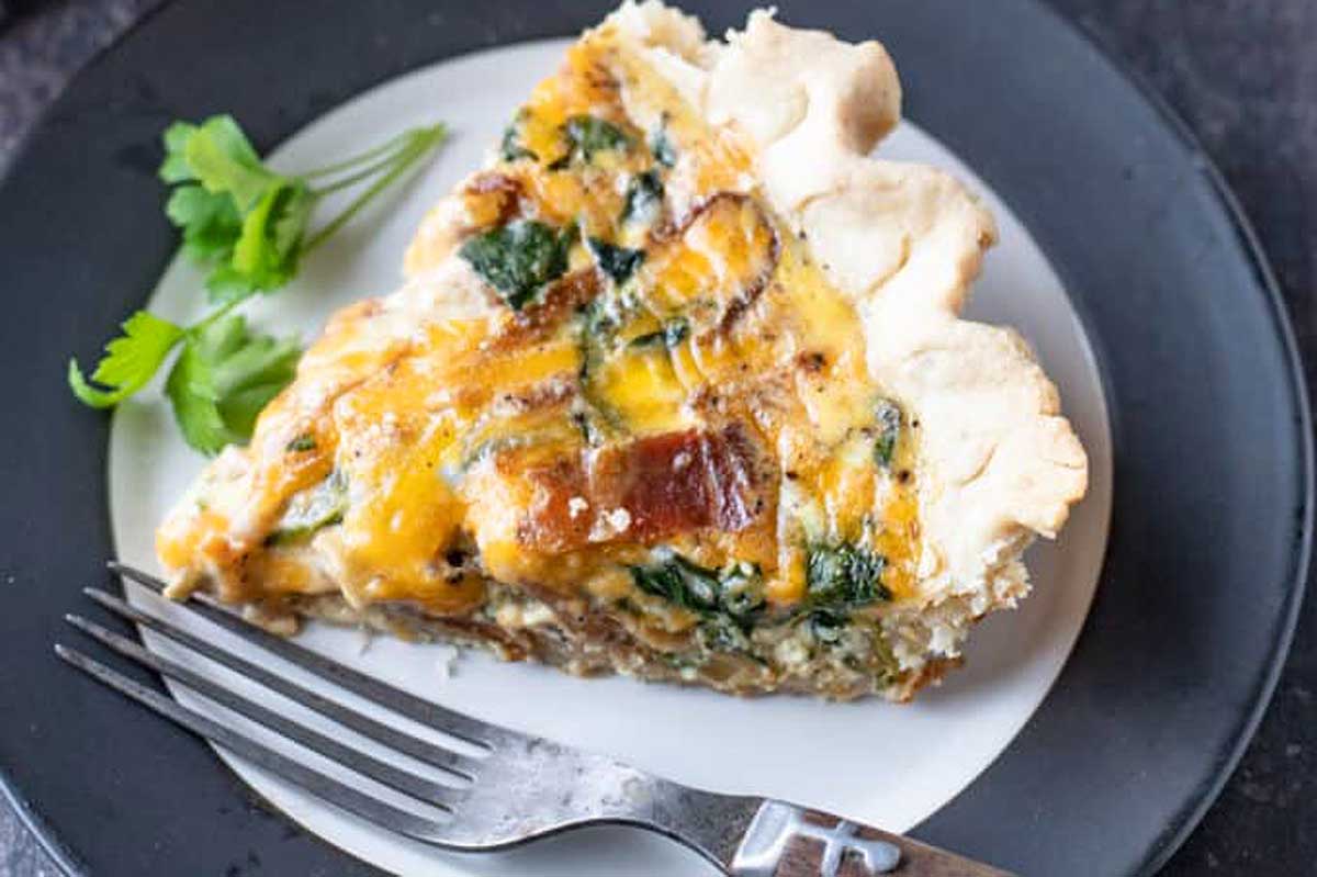 Cooked cheese, vegetable and meat quiche in a glass baking dish.