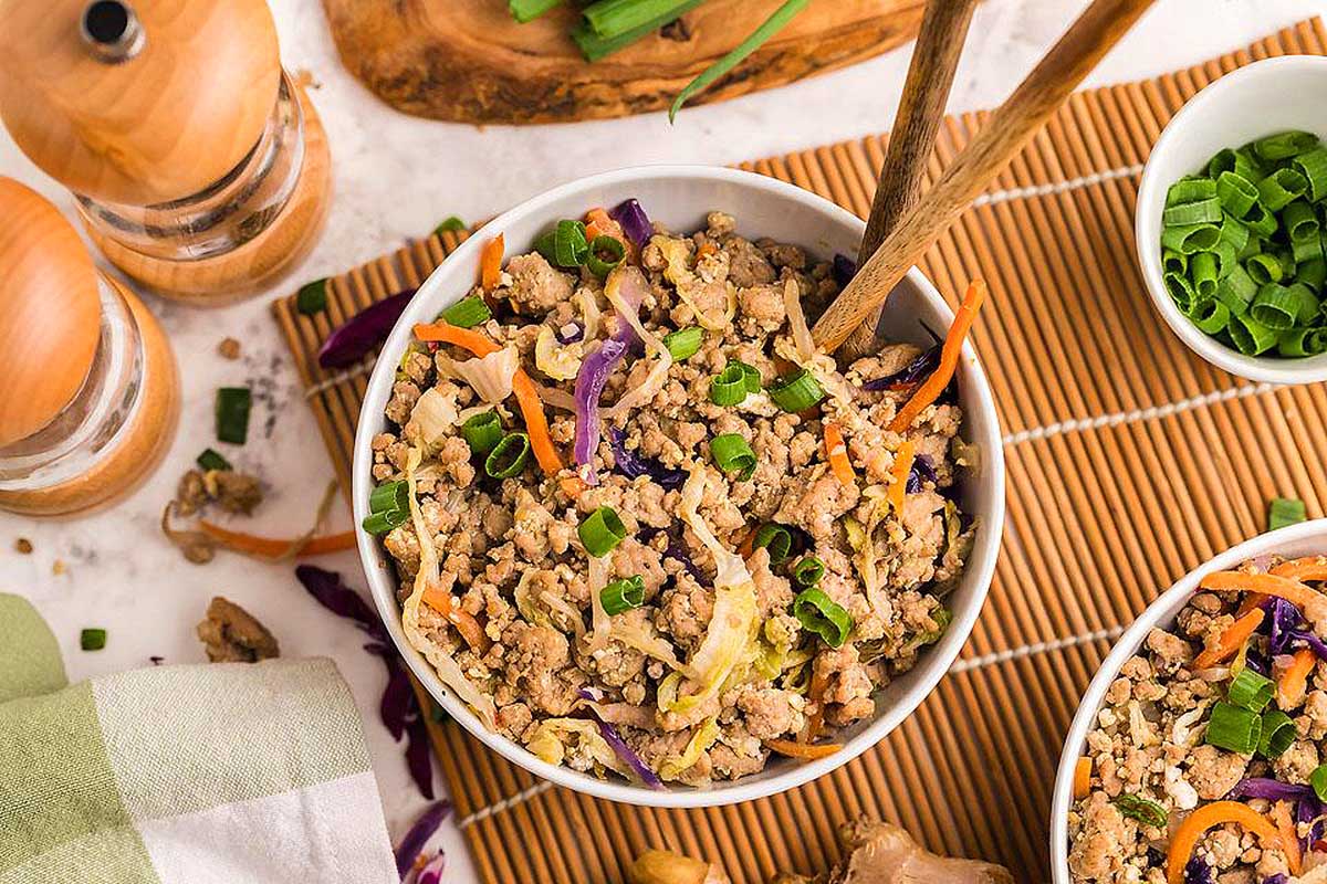 Pork egg roll in a bowl with chopsticks on a mat.