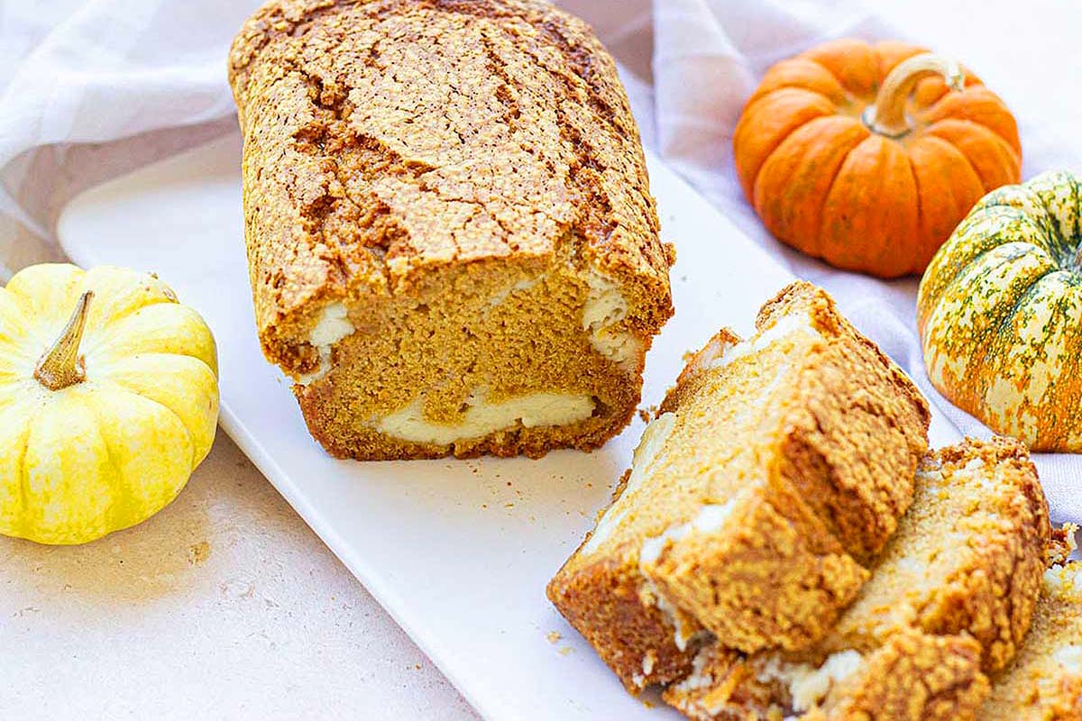 Pumpkin bread on a white plate with pumpkins.
