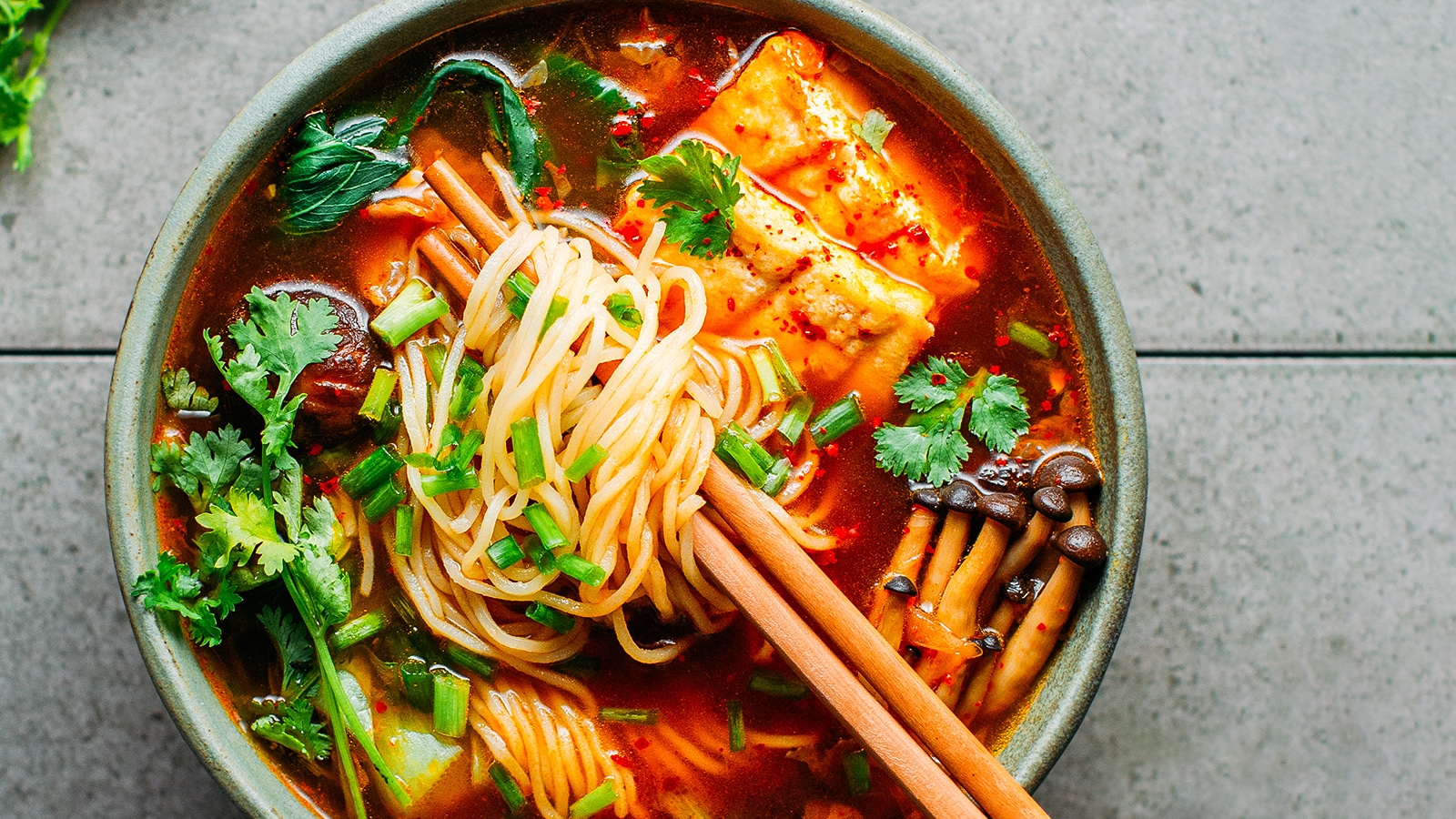 Kimchi noodle soup in a bowl with chopsticks.