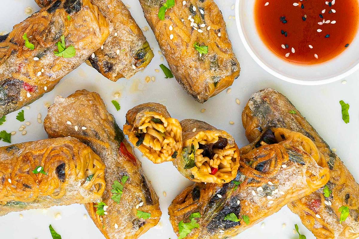 Ramen spring rolls on a platter with dipping sauce.