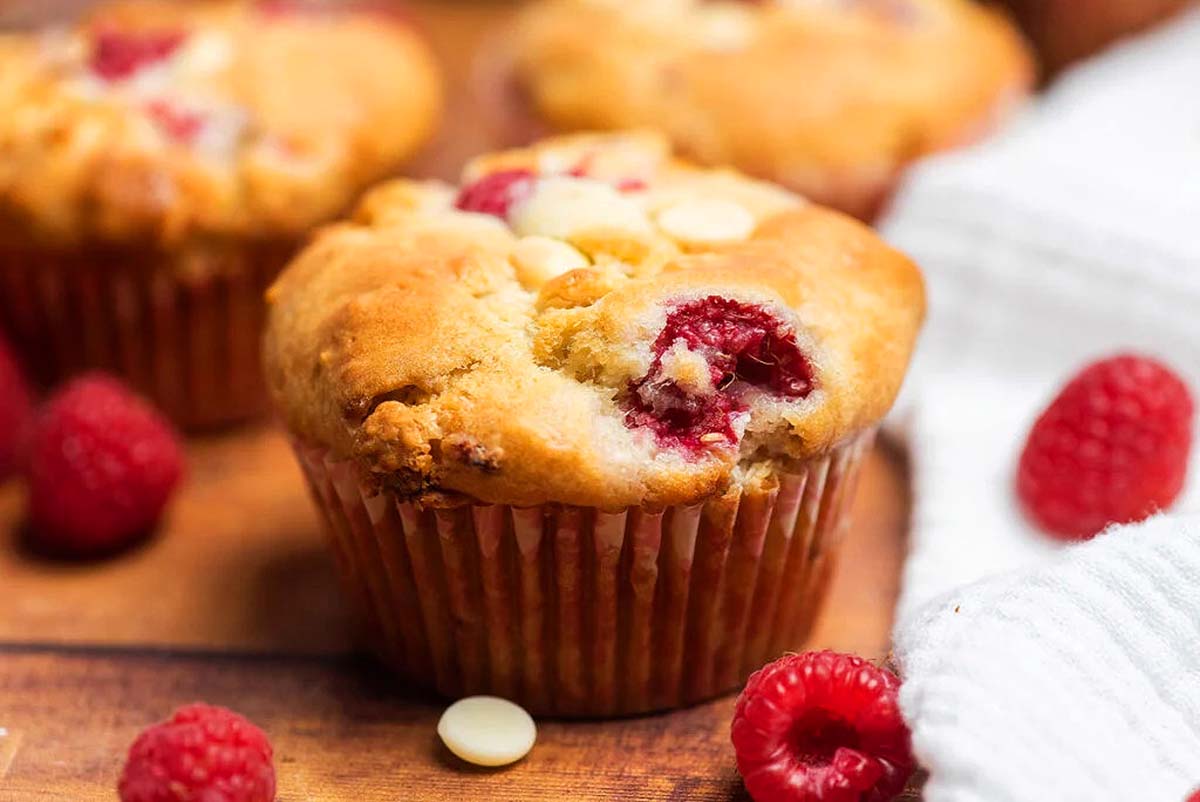 Homemade raspberry muffins on a cutting board.