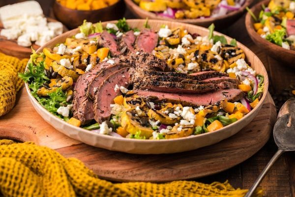 Salad with squash and steak in a bowl.