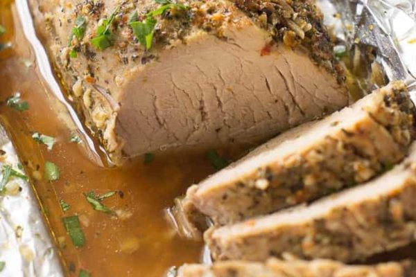 Herb roasted pork tenderloin on a plate with gravy.
