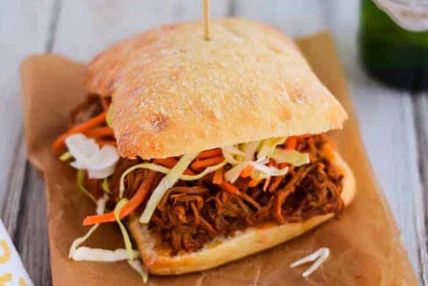 Slow cooker BBQ pork sandwich on parchment paper.