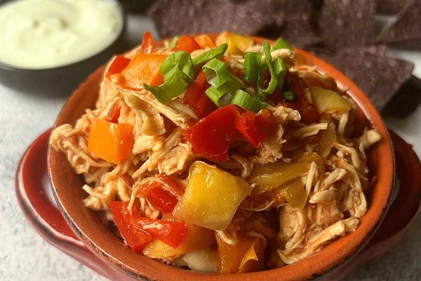 Slow cooker mango chicken in a brown bowl.