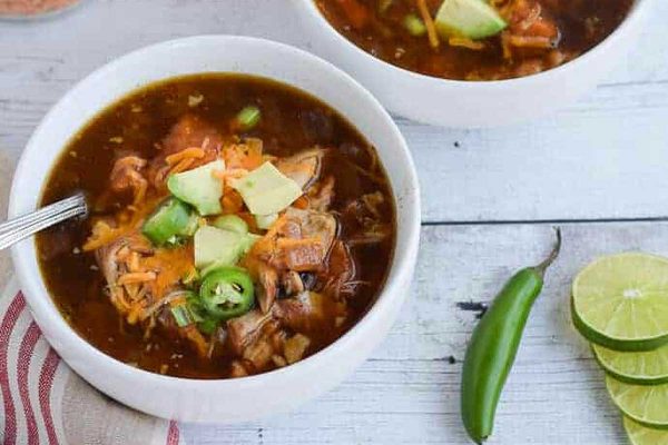 Slow cooker Mexican chicken soup in a white bowl with cheese on top.