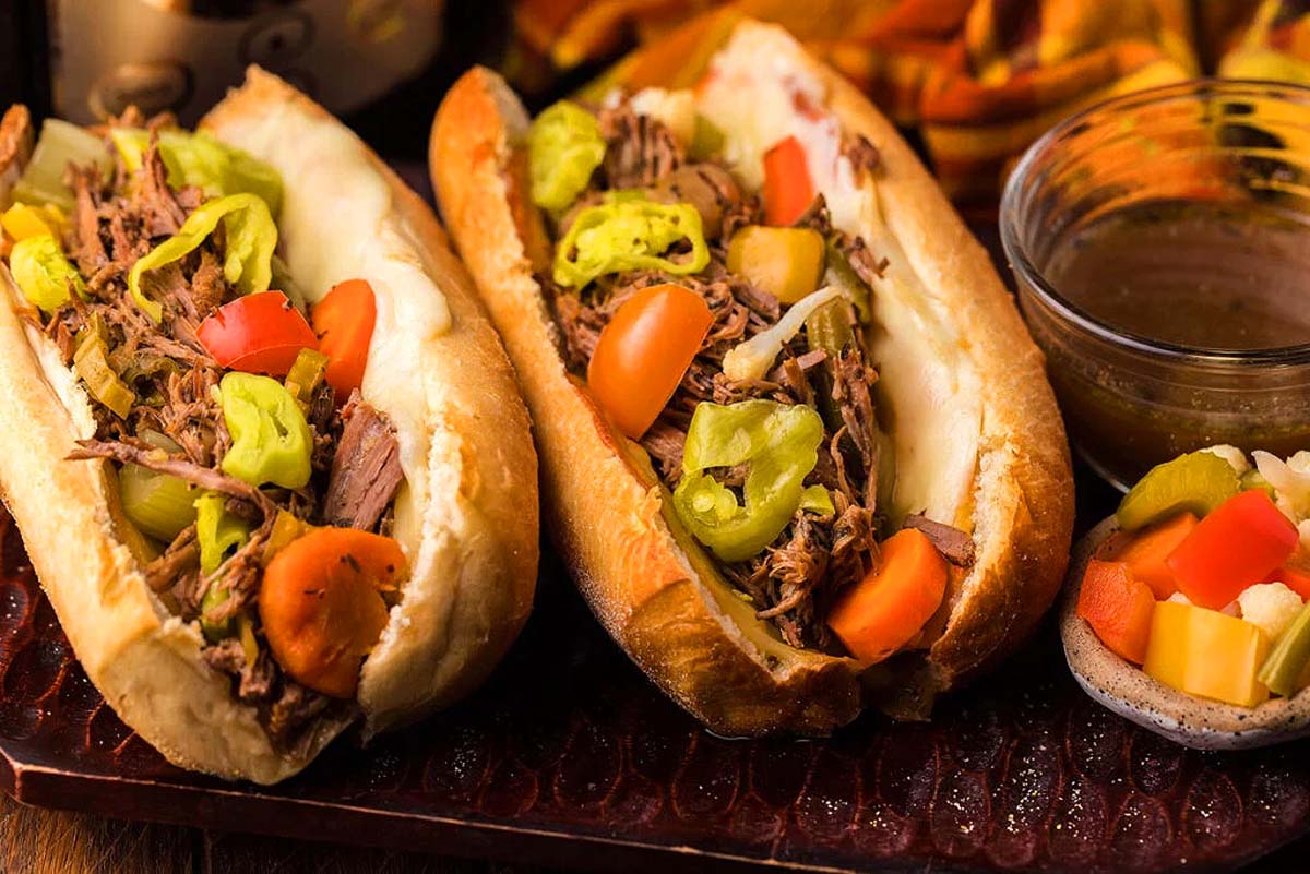 Two Italian beef buns with peppers on top.