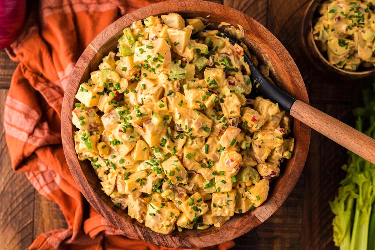 Potato salad in a wood bowl with a spoon. 