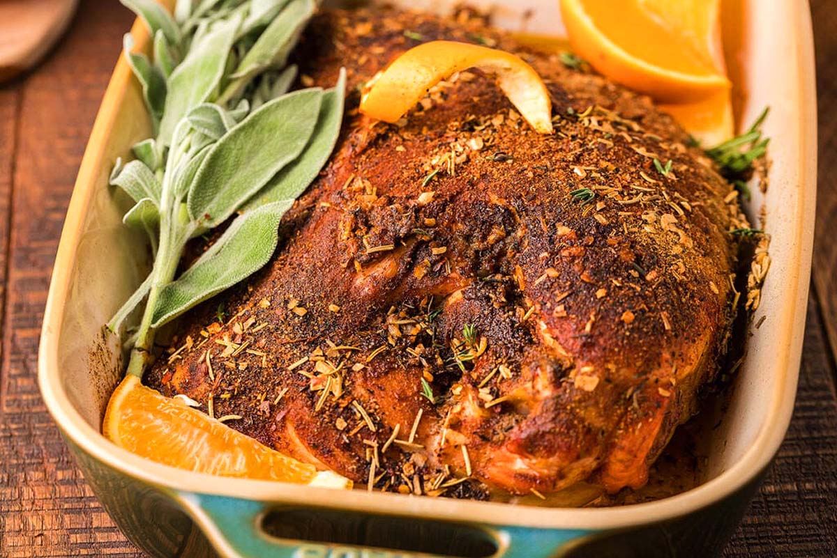 Overhead view of a smoked turkey breast being sliced on a cutting board. 