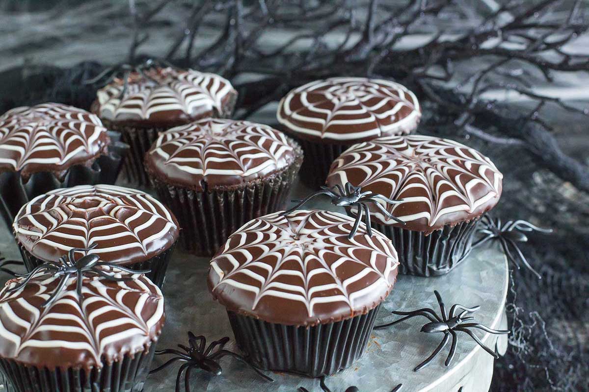 Cupcakes with icing spider webs on top.