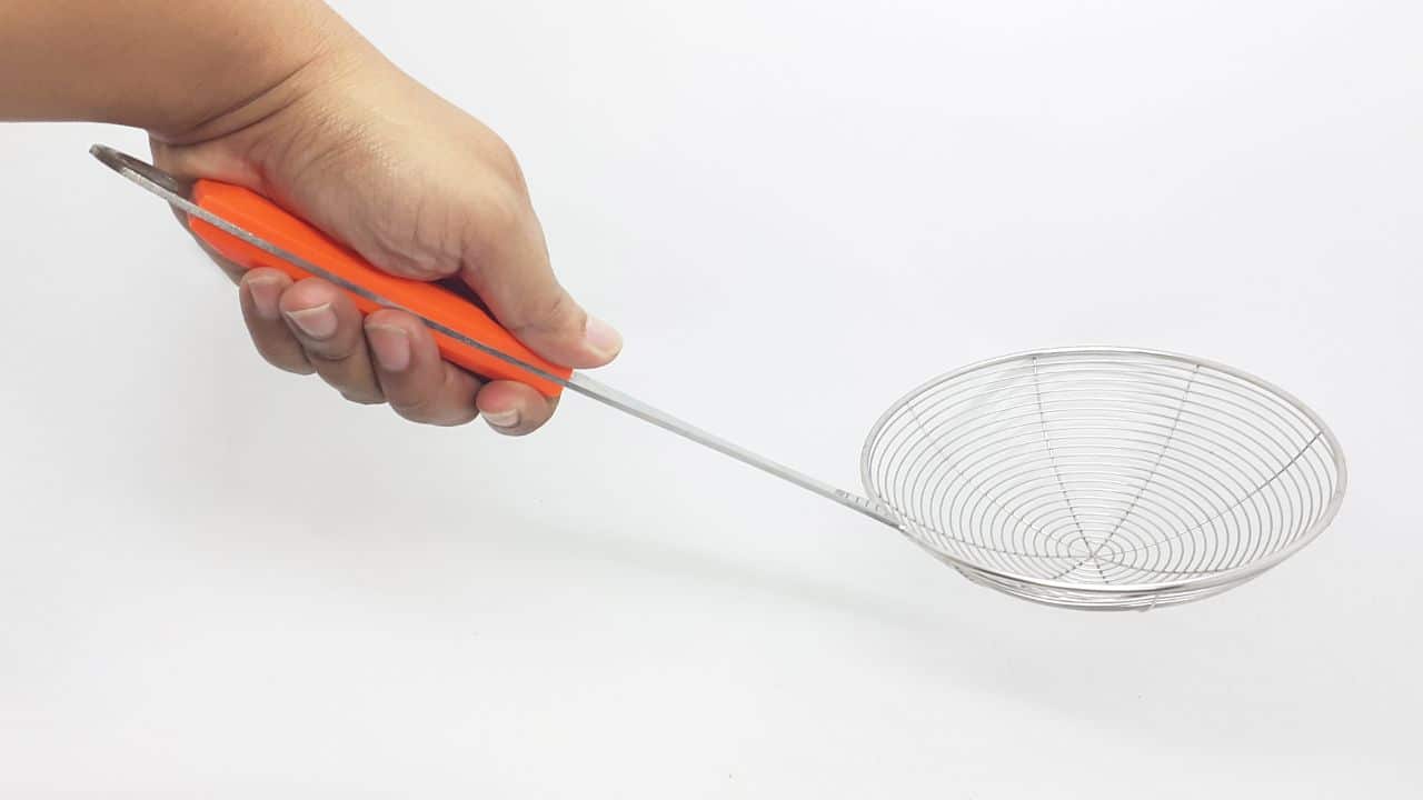 A hand holding a spider strainer tool. 