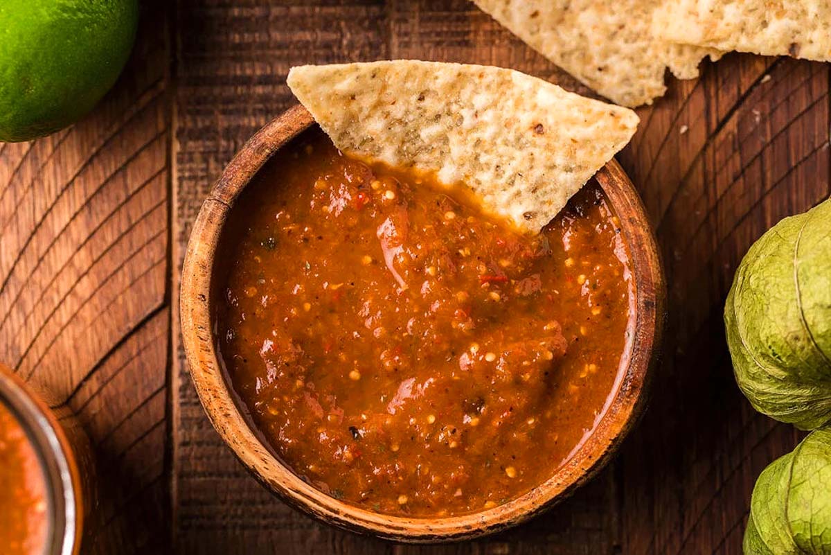 A chip scooping some tomatillo red salsa.
