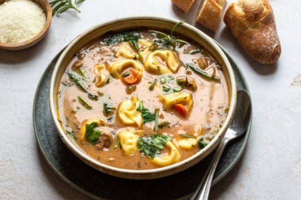tortellini soup with sausage in a bowl with bread