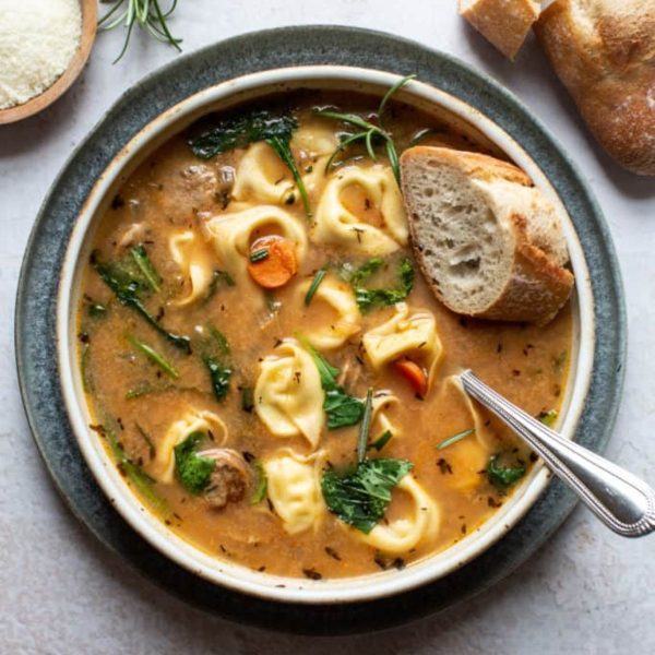 tortellini soup with sausage in bowl with spoon