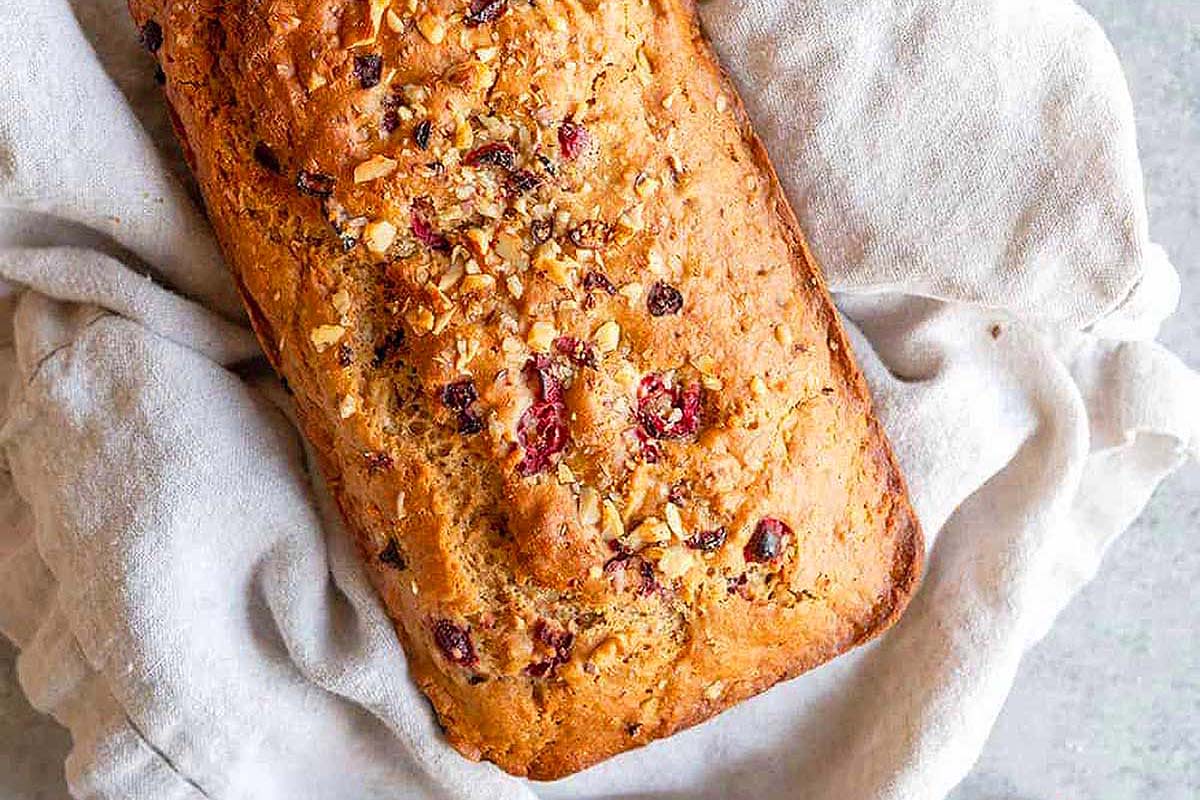 A loaf of cranberry banana bread on a white cloth.