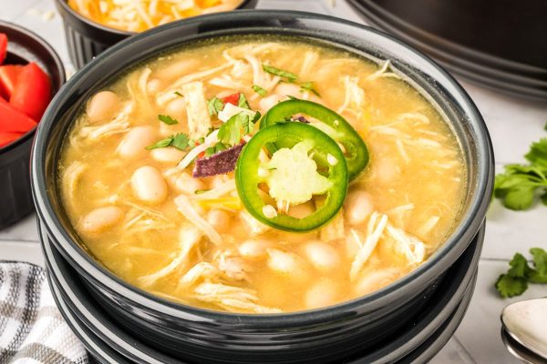 White chicken chili in a black bowl with peppers.