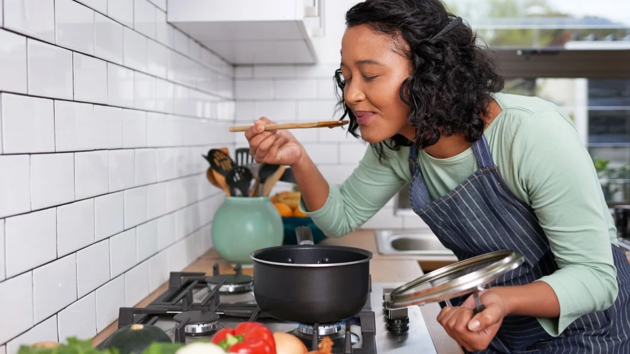 Woman cooking soup on her stove at home.