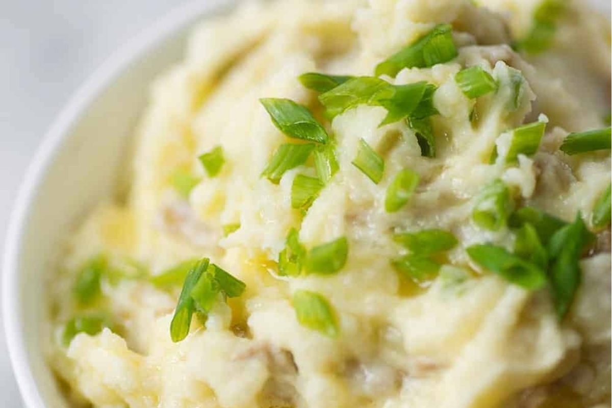 A bowl of mashed potatoes topped with green onions.