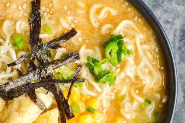A mouthwatering bowl of Japanese ramen with perfectly cooked noodles and a generous topping of corn, exuding the authentic flavors of traditional ramen.