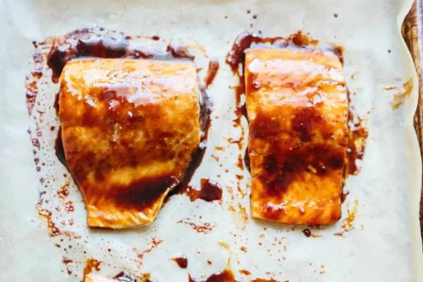 Two Asian-inspired salmon fillets on a baking sheet.