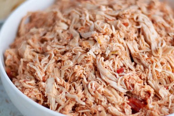 Shredded chicken in a white bowl with tortilla chips.