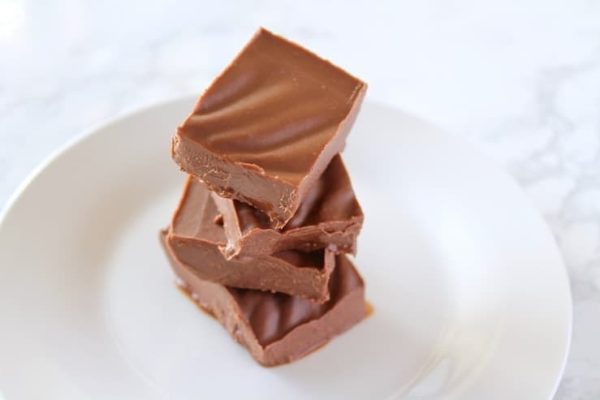 A stack of Christmas-themed chocolate fudge on a white plate.
