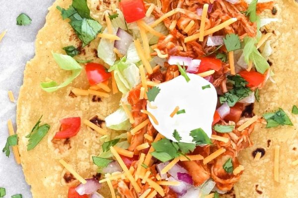 Chicken tacos topped with sour cream and salsa.