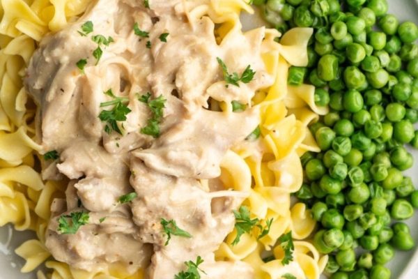 A plate of pasta with chicken and peas.