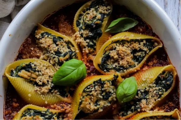 Stuffed shells with spinach and cheese in a white dish.