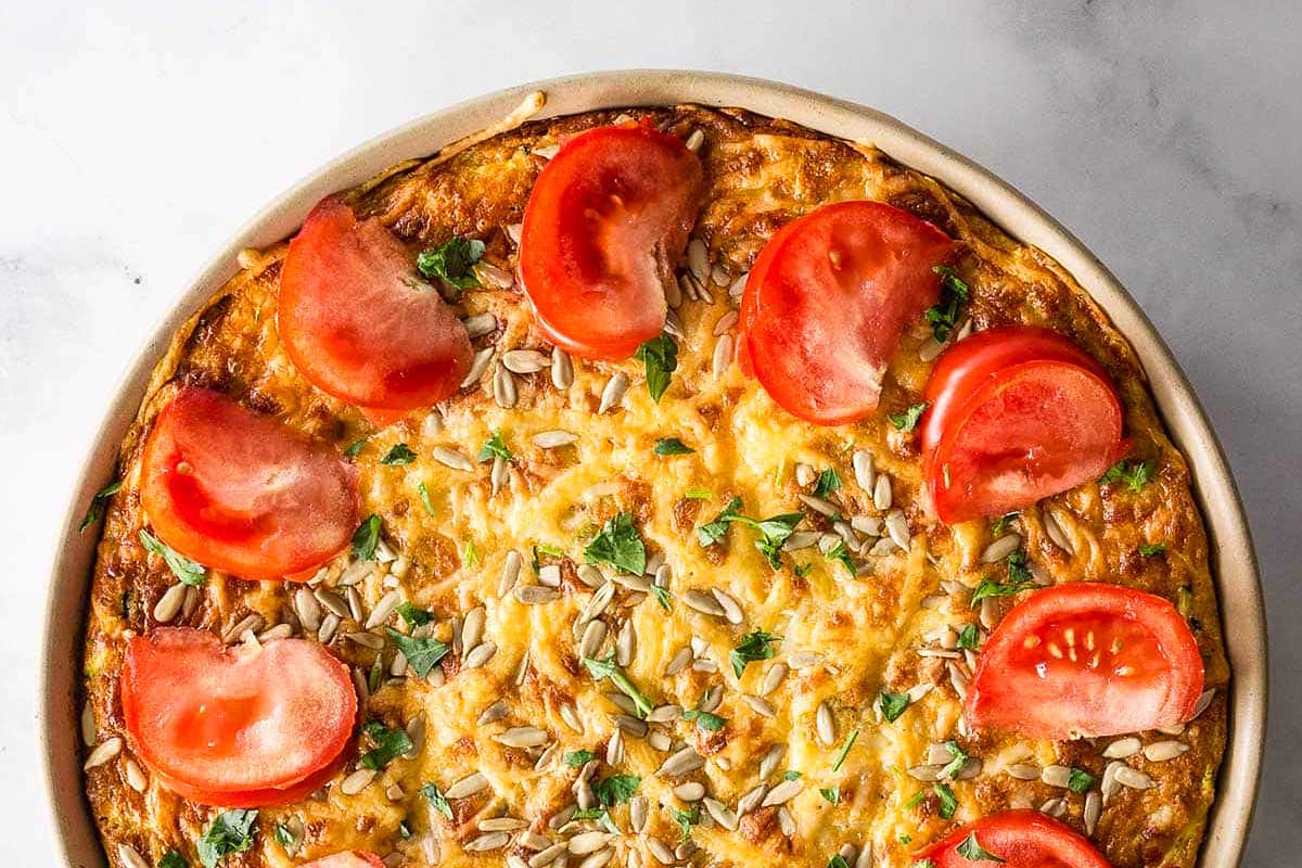 A dish with a tomato and onion on top.