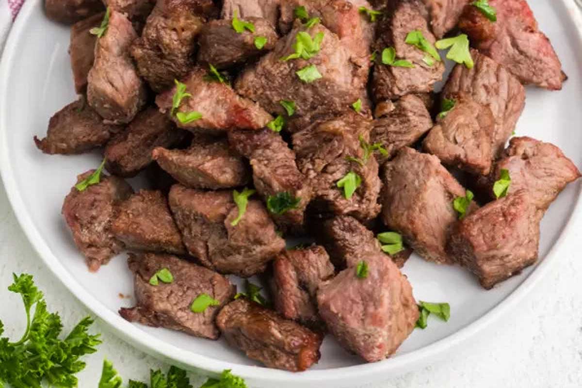 Grilled steak on a white plate with parsley.