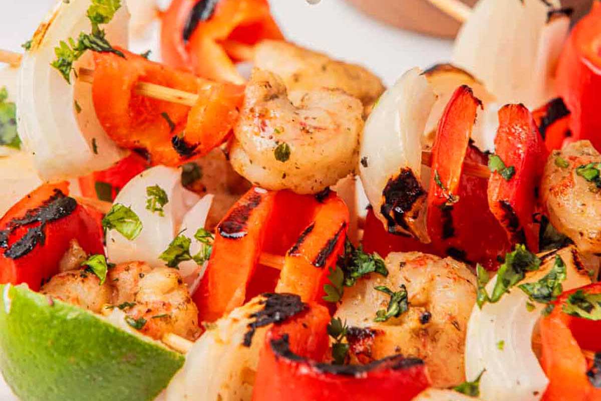 Shrimp and pepper skewers arranged on a white plate.