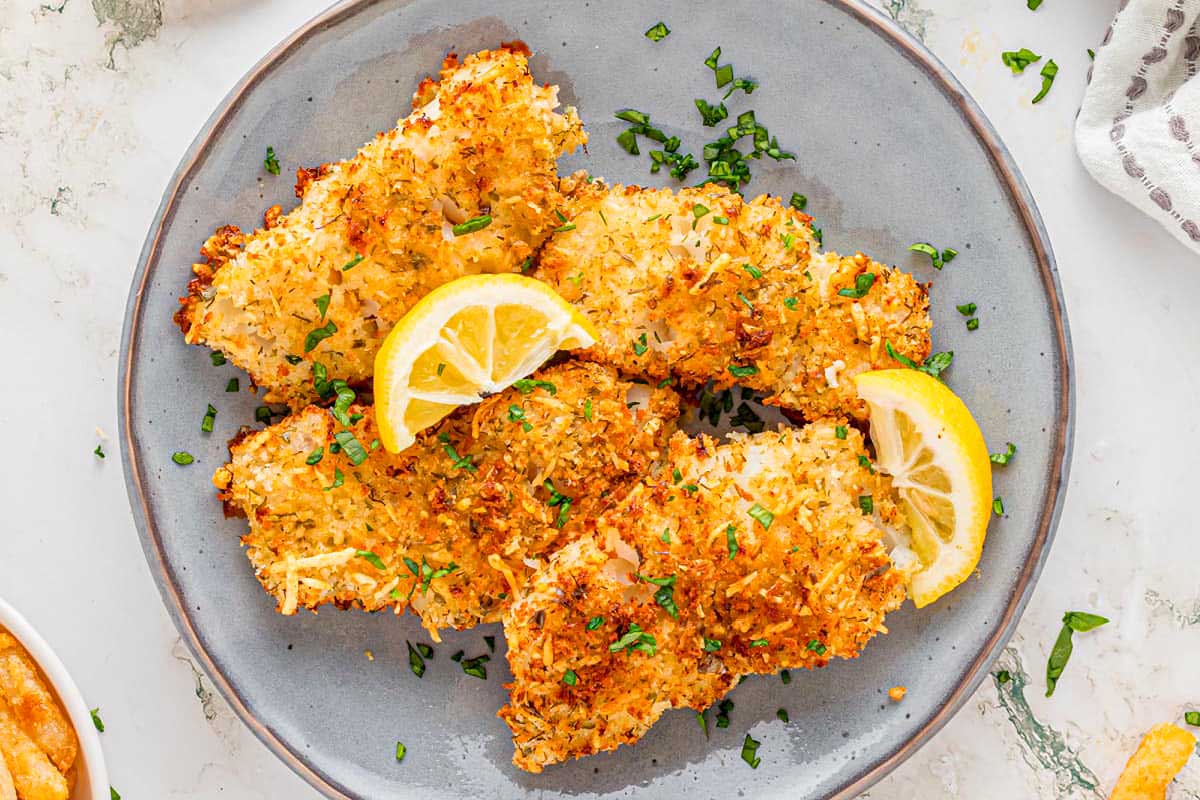 A plate of fried fish with lemon wedges.
