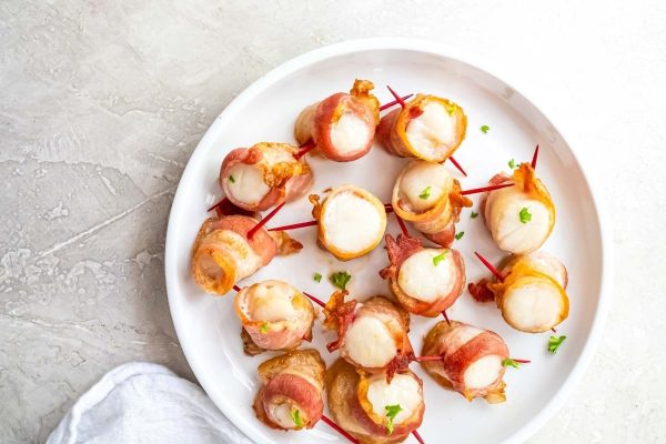 Bacon wrapped skewers on a white plate.