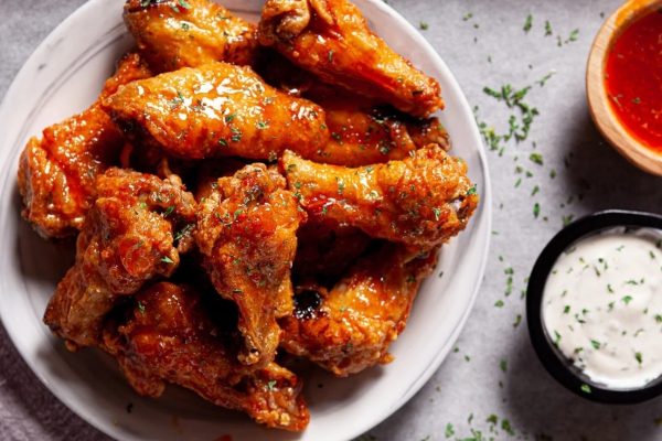 Thanksgiving potluck chicken wings with sauce and dipping sauce.