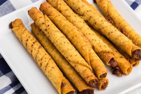 Cheesy tortilla sticks on a white plate with a checkered napkin.