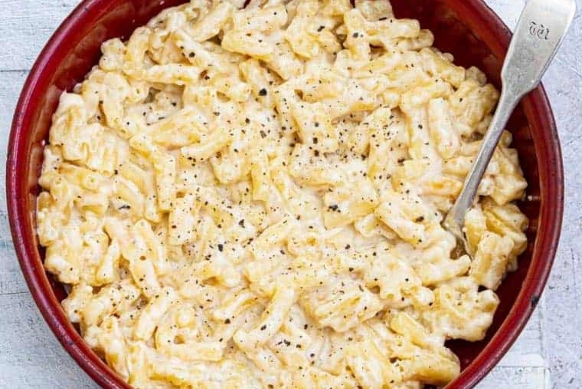 Winter comfort food - macaroni and cheese served in a red bowl with a spoon.