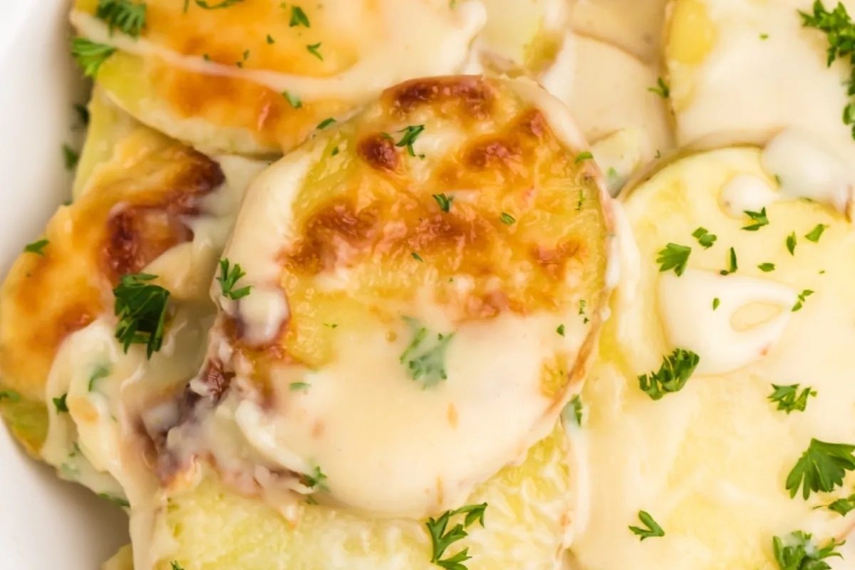 Cheesy potatoes in a white bowl with parsley.