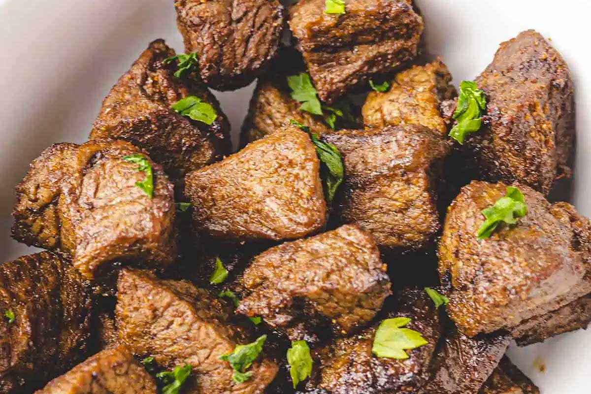Beef tenderloin in a white bowl with herbs.