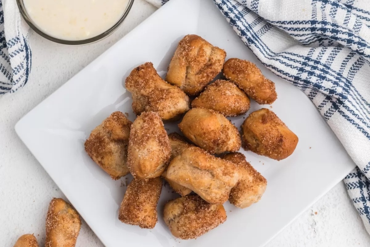 A plate of cinnamon-fried doughnuts served with a glass of milk.