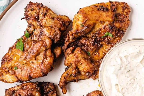 Chicken wings on a plate with a dipping sauce.