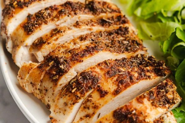 Sliced chicken breast on a plate with a salad.